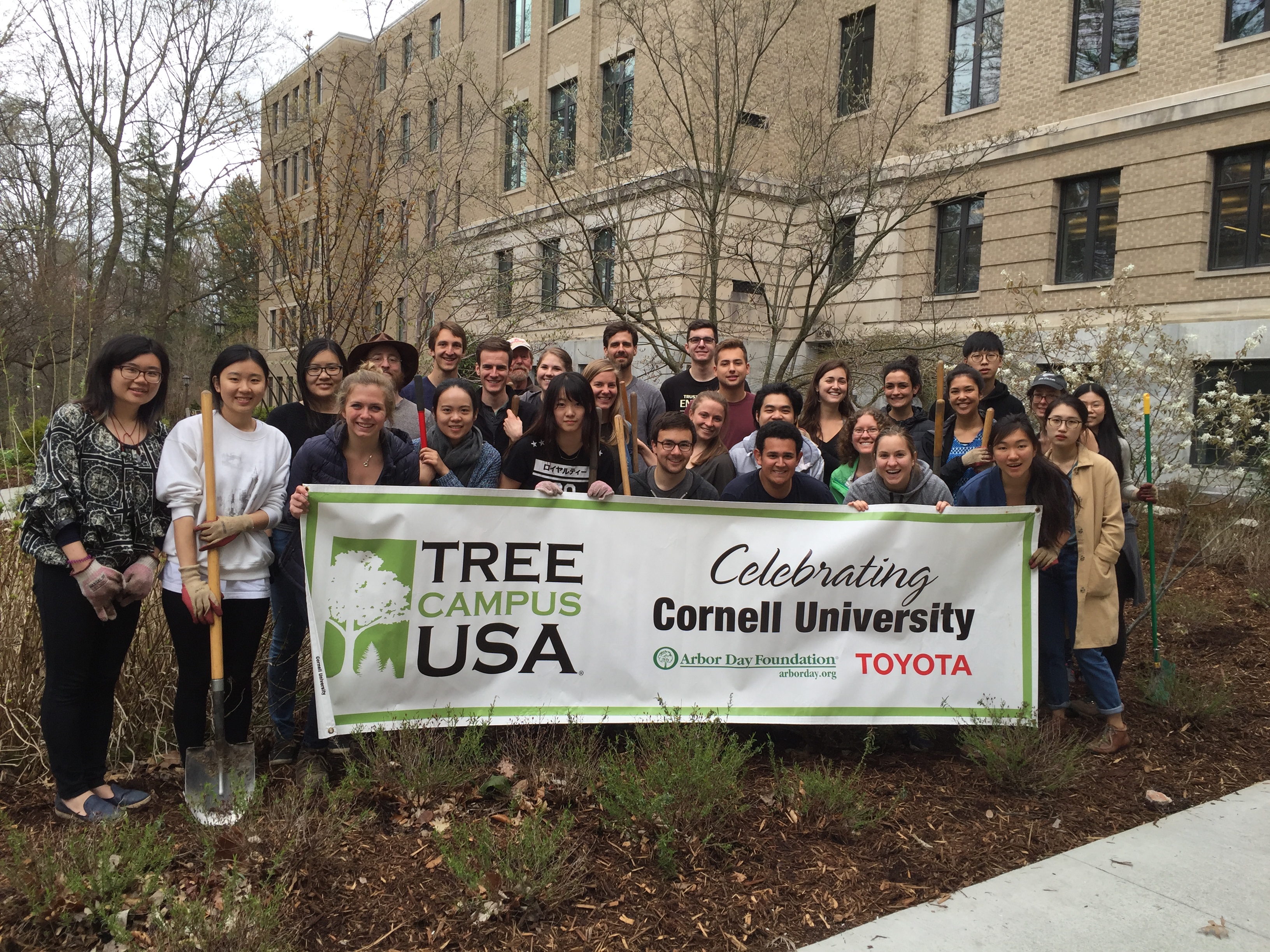 Cornell Landscape Improvement Partners (CLIPers) committee gathered around Tree Campus USA  sign Arbor Day 2016